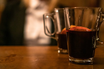 Beauty, elegant business woman with two glasses of mulled wine with orange and lemon inside the bar in basement. Wroclaw, Poland