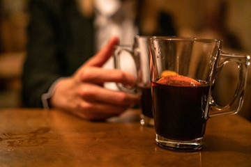 Beauty, elegant business woman with two glasses of mulled wine with orange and lemon inside the bar in basement. Wroclaw, Poland