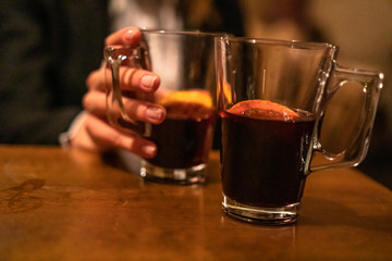 Beauty, elegant business woman with two glasses of mulled wine with orange and lemon inside the bar in basement. Wroclaw, Poland