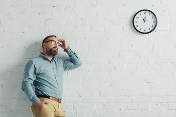 pensive businessman in shirt and glasses looking away in office