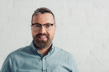 handsome businessman in shirt and glasses smiling and looking at camera