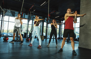 A group of muscular athletes doing workout at the gym. Gymnastics, training, fitness workout flexibility. Active and healthy lifestyle, youth, bodybuilding. Training in lunges and stretching exercises