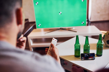 Backing view of man holds remote controller in hand and turning on TV