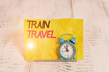 Word writing text Train Travel. Business photo showcasing to make a journey a long distance by using rail transit Mini blue alarm clock stand tilted above buffer wire in front of notepaper