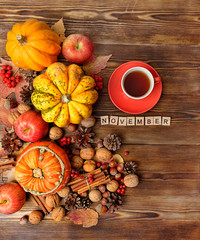 November time concept. autumn composition with pumpkins, apple, nuts and tea cup. autumn cozy still life on wooden table. fall harvest season, thanksgiving holiday background. top view