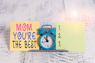 Writing note showing Mom You Re The Best. Business concept for Appreciation for your mother love feelings compliment Mini blue alarm clock standing above buffer wire between two paper