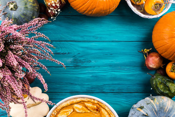 Autumn thanksgiving moody background with pumpkin pie, different pumpkins, fall fruit and flowers on green rustic wooden table. Flat lay - 301370036