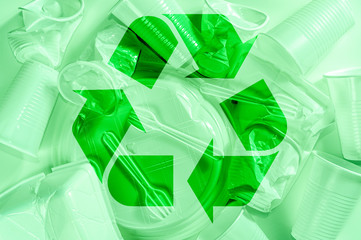 Disposable plastic tableware and recycling sign on a light background in green colors. Minimalistic...