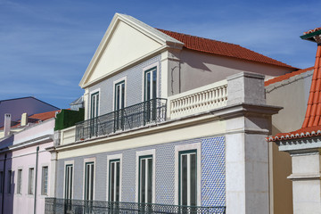 A beautiful architecture of the traditional tiled walled facade with large glass doors and windows and the iron balcony in the city of Lisbon in Portugal