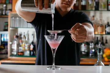 Professional barman making cosmopolitan cocktail.