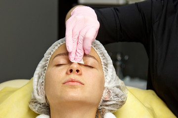 contour plastic. A cosmetologist injects a botulinum toxin to tighten and smooth out wrinkles on...