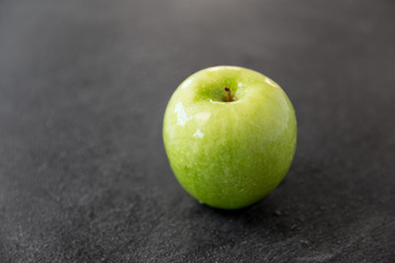 fruits, diet, eco food and objects concept - ripe green apple on slate stone background