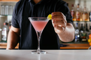 Professional barman making cosmopolitan cocktail.