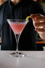 Professional barman making cosmopolitan cocktail.