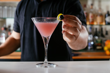 Professional barman making cosmopolitan cocktail.