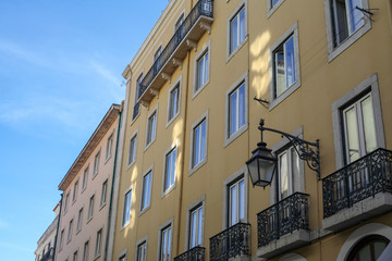 Fototapeta na wymiar The traditional facade wall architectures of buildings with large glass doors and windows, balconies and iron lamps in the city of Rome in Italy