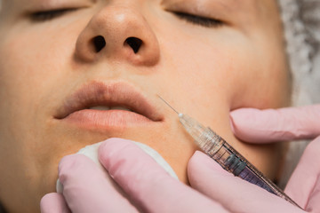 contour plastic. A cosmetologist injects a botulinum toxin to tighten and smooth out wrinkles on...
