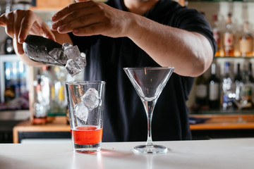 Barman making red cocktail. Professional bartender preparing Manhattan cocktail. 