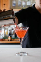 Barman making red cocktail. Professional bartender preparing Manhattan cocktail. 