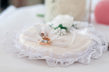 Fototapeta na wymiar Pair of golden wedding rings on the white pillow