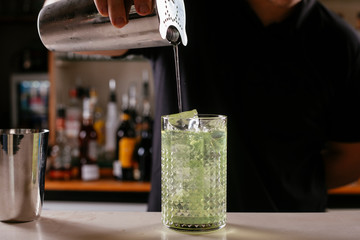 Close up of barman making green cocktail