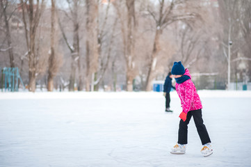 Girl in the winter at the rink. A girl in a pink jacket is skating. Background for text.