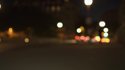Defocused Night City Lights near Eiffel Tower in Paris. Color Blurred bokeh of moving cars and bus in street. Static Shot 4K UHD. Lens flares, wide shot. - Powered by Adobe