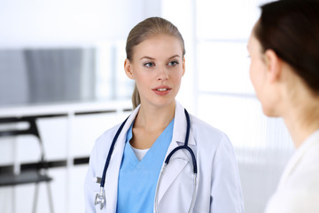 Fototapeta premium Doctor and patient during consultation. Physician at work filling up medication history record while sitting in emergency hospital, portrait shoot. Medicine and health care concept