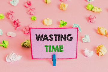 Writing note showing Wasting Time. Business concept for act of spending time doing something that is unnecessary Colored crumpled papers empty reminder pink floor background clothespin