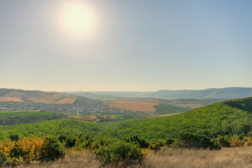 Countryside and beautiful sky. Green hills, meadows and arable land. Summer landscape. Caucasus mountains, vineyards