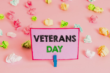 Writing note showing Veterans Day. Business concept for a public holiday to honour US veterans and victims of all wars Colored crumpled papers empty reminder pink floor background clothespin