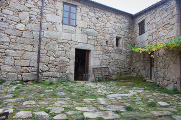 Backyard of old house in village. Stone medieval building with open entrance and windows. Open door to the ancient rural house. Exterior of medieval architecture. 