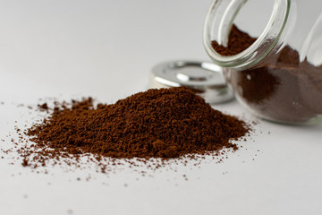 lass jar with ground coffee upside down. Rashes ground coffee from a jar on a white background.