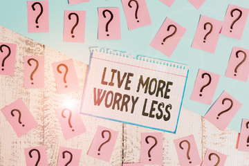 Writing note showing Live More Worry Less. Business concept for Have a good attitude motivation be careless enjoy life Scribbled and crumbling papers with thick cardboard above wooden table