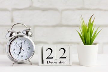 calendar from white wooden cubes and an alarm clock on the table 22 December on yard