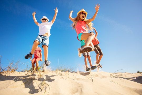 Group of children jump up from sand dune