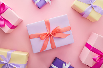 top view of colorful gift boxes with ribbons and bows on pink background