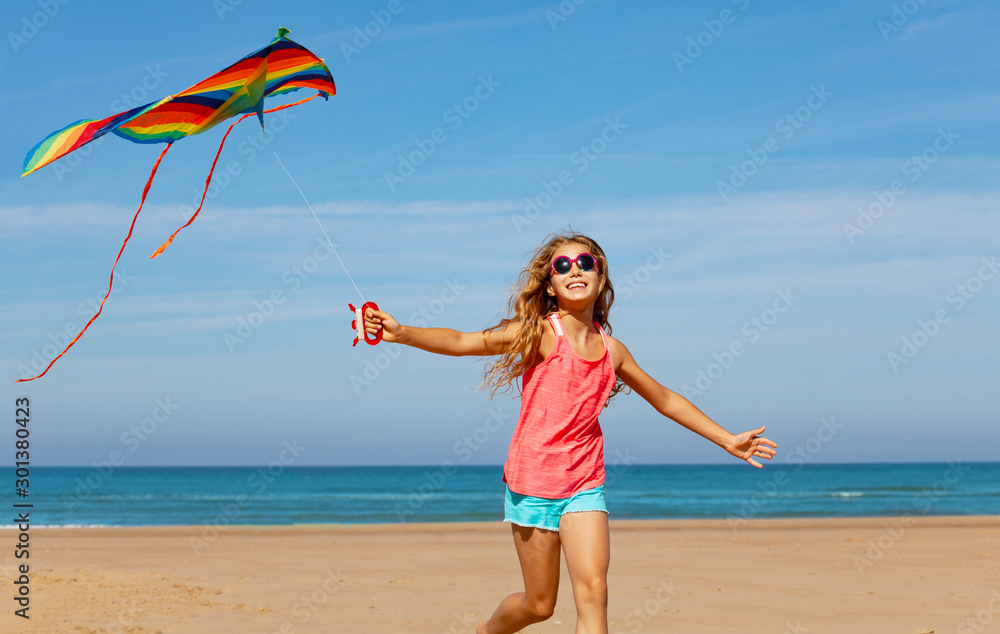 Wall mural happy carefree girl run with kite on a sand beach