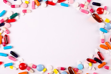 Flat lay composition with bunch of different colorful pills in scattered all over the table. Pile of opened medication on paper textured background. Close up, copy space.