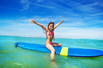 Beautiful little girl surfer sit on surfboard