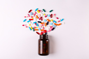 Flat lay composition with bunch of different colorful pills scattered from the bottle over the...