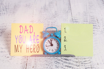 Writing note showing Dad You Are My Hero. Business concept for Admiration for your father love feelings compliment Mini blue alarm clock standing above buffer wire between two paper