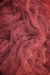 Full frame background of red plastic fishing net, which when abandoned represents the majority of large plastic pollution in the oceans
