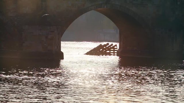 Sun flare in hand water. In the background is a large, saty bridge.