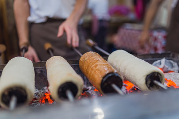 Chimney cake preparation. Chimney cake is being roasted over the fire. Street food concept.