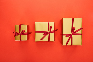 flat lay with three golden gift boxes on red background