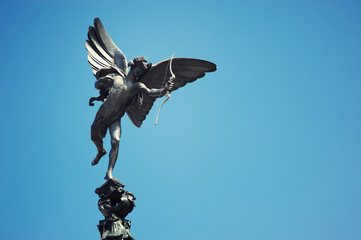 Statue of Anteros (brother of the Greek god Eros) standing in sunny blue sky at the top of the...