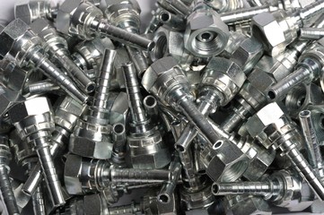 a pile of screws and bolts and connectors for hydraulic pipes: Various steel nuts and bolts