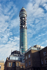Communications tower decorated with satellite dishes standing outdoors against blue sky in London, UK