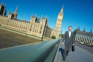 British businessman walking with briefcase on Westminster Bridge with Big Ben and the Houses of...